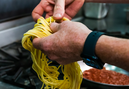 Pair of hands detangling spaghetti pasta